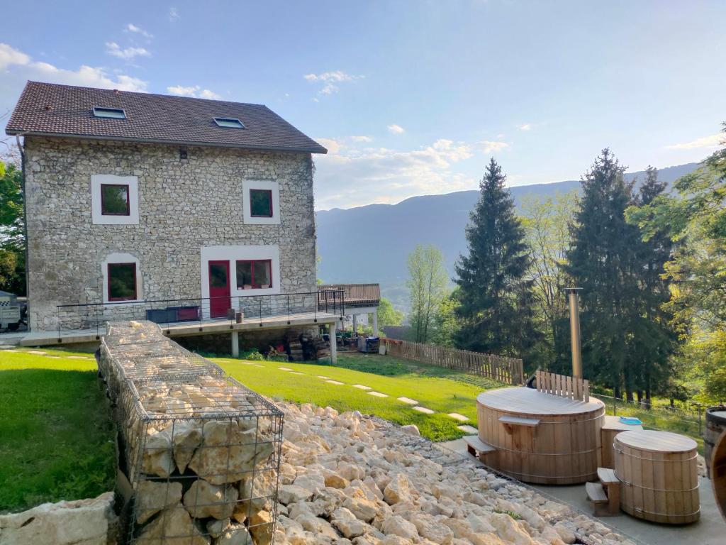 a stone house with a stone wall and two tables at Maison d'Hôtes L'Etiquette in Seyssel