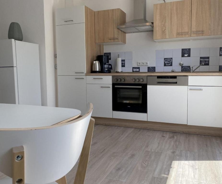 eine Küche mit weißen Schränken und einem Tisch darin in der Unterkunft SAD150 - Moderne Monteurwohnungen in Schwandorf mit Balkon in Schwandorf in Bayern