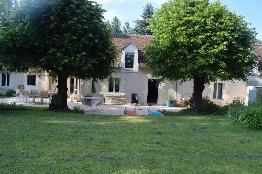 una casa con dos árboles delante de un patio en La Métairie du Moulin de Meusnes, en Meusnes