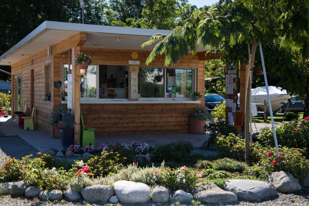 un pequeño edificio con flores delante en Camping Eden Glamping, en Dormelletto