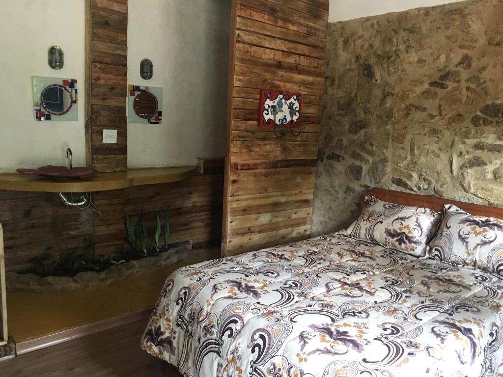 a bedroom with a bed and a stone wall at Pousada Rancho Flores in Caeté