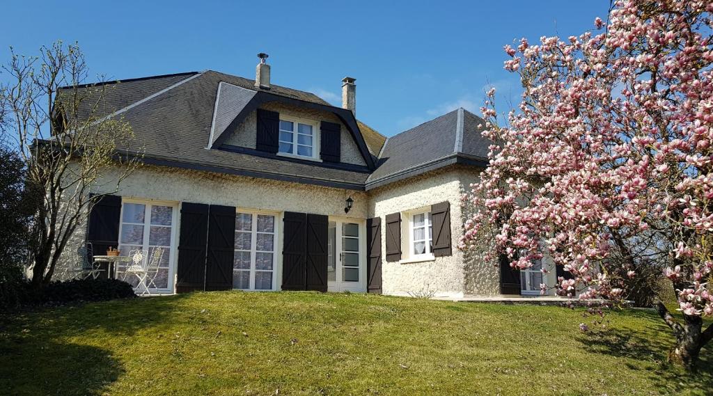 ein Haus mit einem blühenden Baum davor in der Unterkunft LA MAISON DU MUGUET - Accueil Chevaux - Horse Friendly in Liart