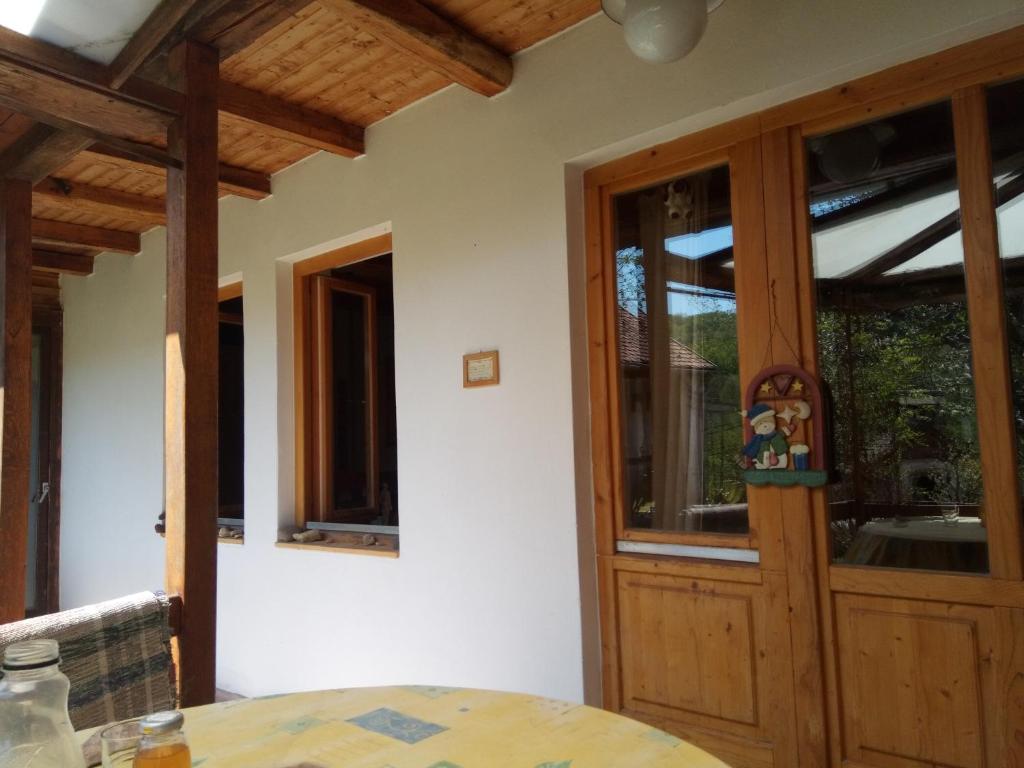 a dining room with a wooden door and windows at Mackólak Vendégház és Ökoporta in Hosszúhétény-Szőlőhegy