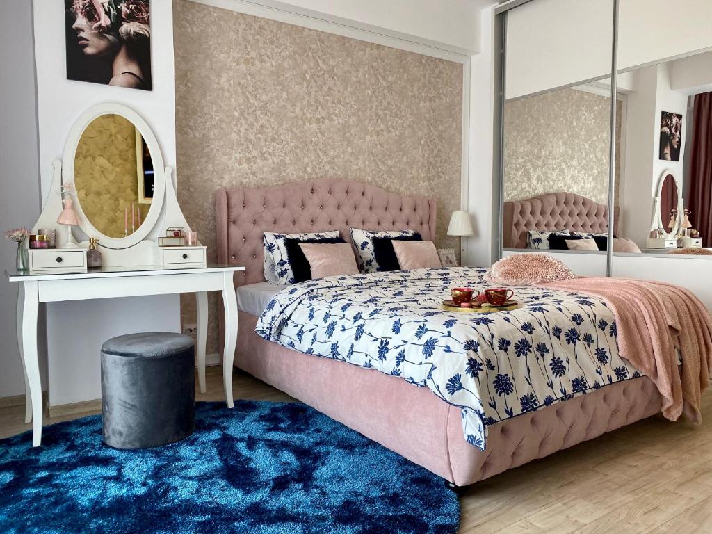 een slaapkamer met een roze bed en een blauw tapijt bij Bucharest Mall Studio in Boekarest