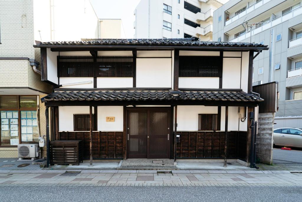 a building with a brown door in a city at Casaya TABI-NE in Kanazawa