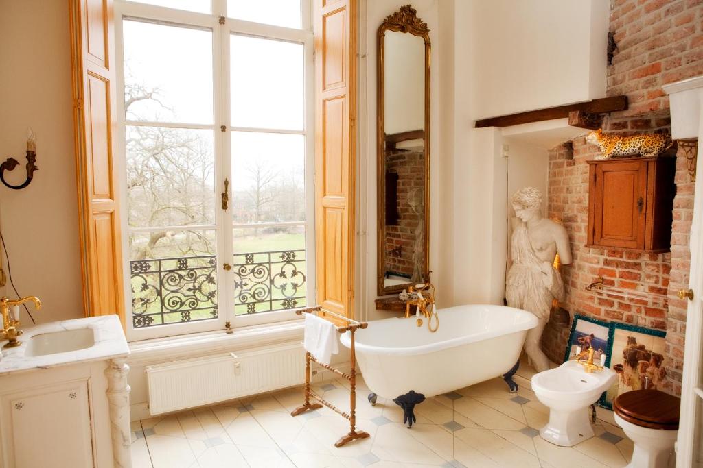 een badkamer met een bad, een wastafel en een raam bij Kasteel Sterkenburg in Driebergen