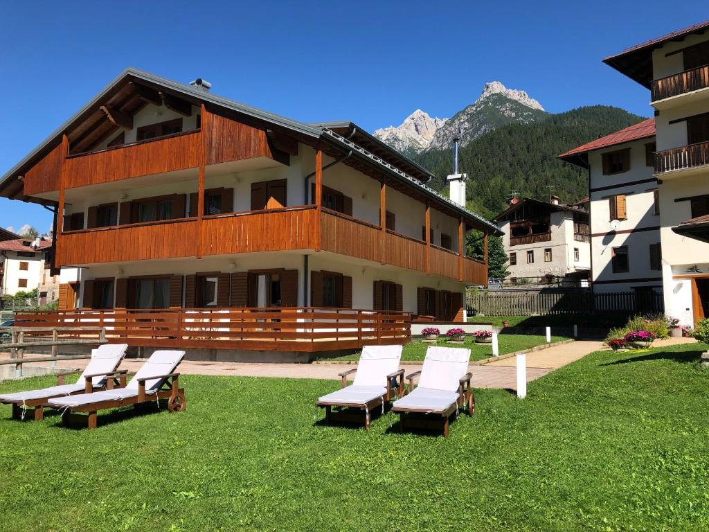 a building with a bunch of lounge chairs in the grass at Residence Al Lago in Auronzo di Cadore