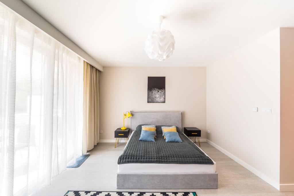 a bedroom with a bed with two blue pillows at Raval Apartments - Soft Black in Rewal
