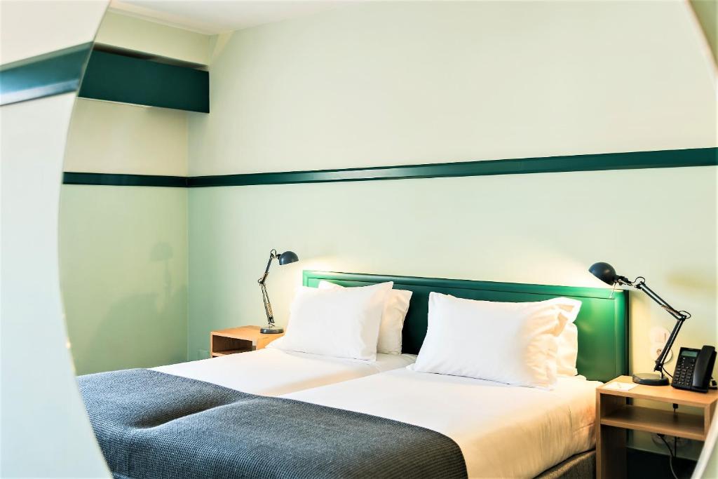 a bedroom with a bed with white sheets and two lamps at Amazonia Lisboa Hotel in Lisbon