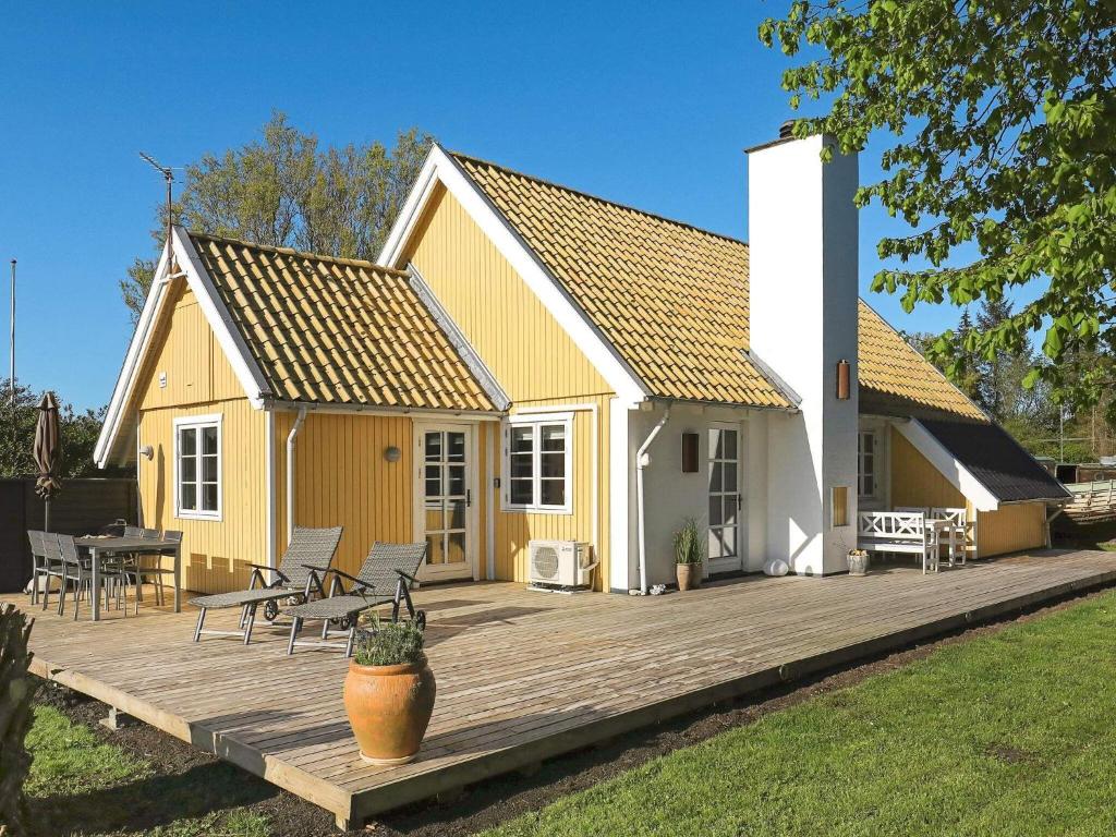 une maison jaune et blanche avec une terrasse en bois dans l'établissement Holiday home Frørup IV, à Frørup