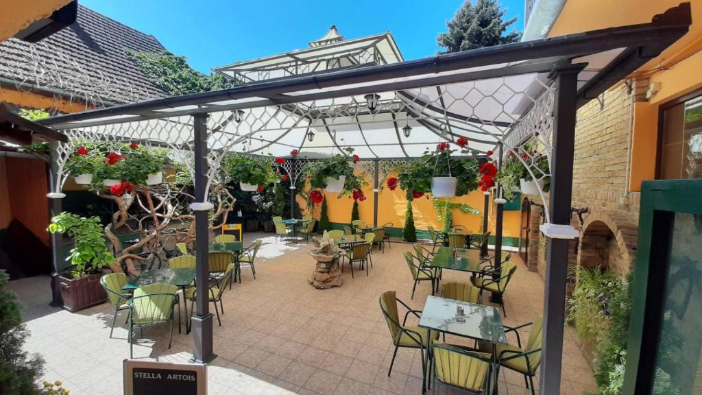 eine Terrasse mit Tischen und Stühlen unter einer Pergola in der Unterkunft Villa Gurman 024 in Bačka Topola