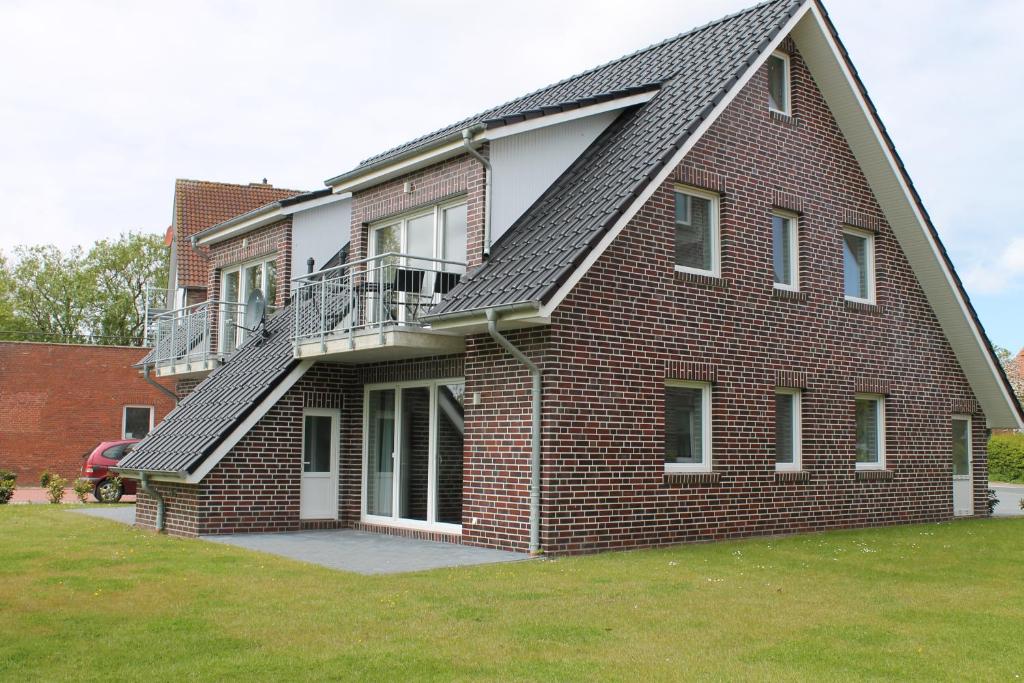 a brick house with a balcony on the side of it at Haus Seesturm in Neßmersiel