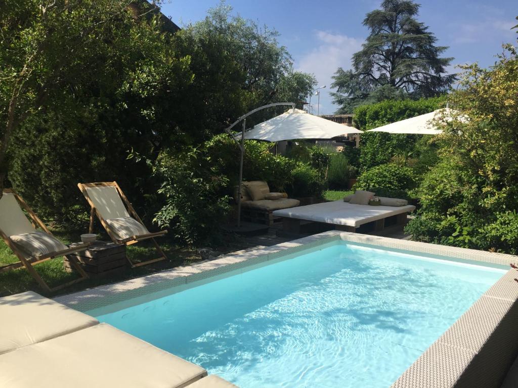 una piscina en un patio con sillas y sombrillas en Il Giardino Segreto, en Iseo
