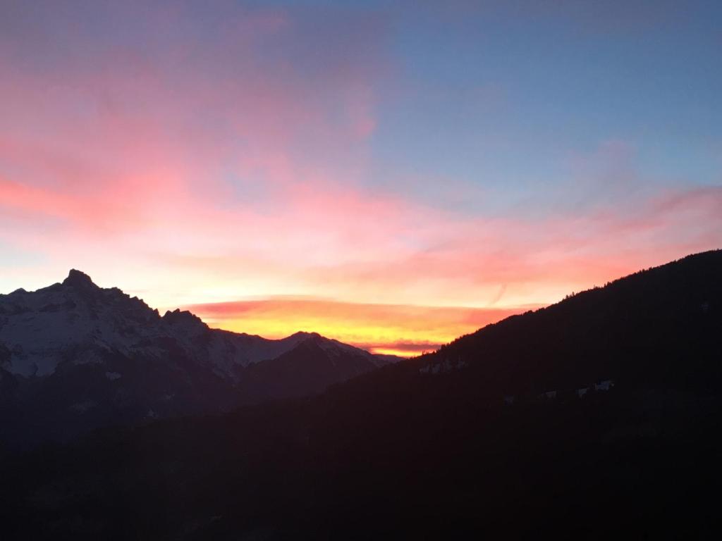 a sunset over a mountain range with the sun setting at Chalet Ingas in Troistorrents