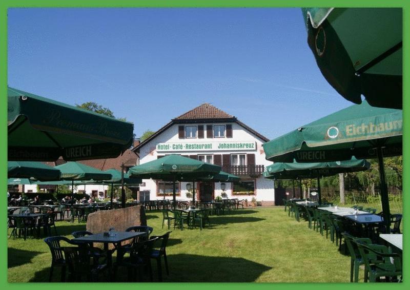 eine Gruppe von Tischen und Sonnenschirmen vor einem Gebäude in der Unterkunft Hotel-Restaurant Johanniskreuz in Trippstadt