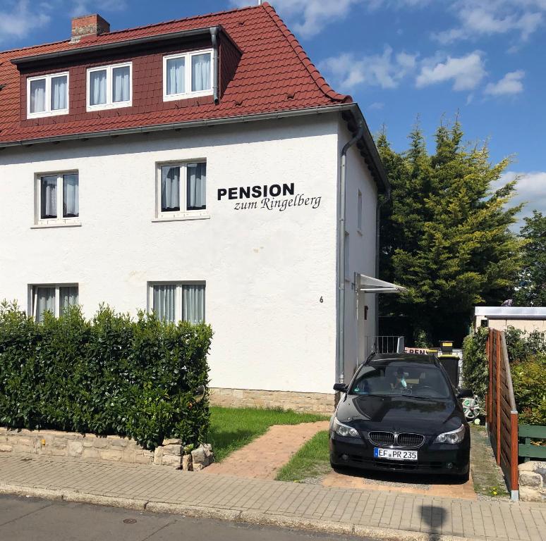 ein Auto, das vor einem weißen Gebäude parkt in der Unterkunft Pension zum Ringelberg in Erfurt