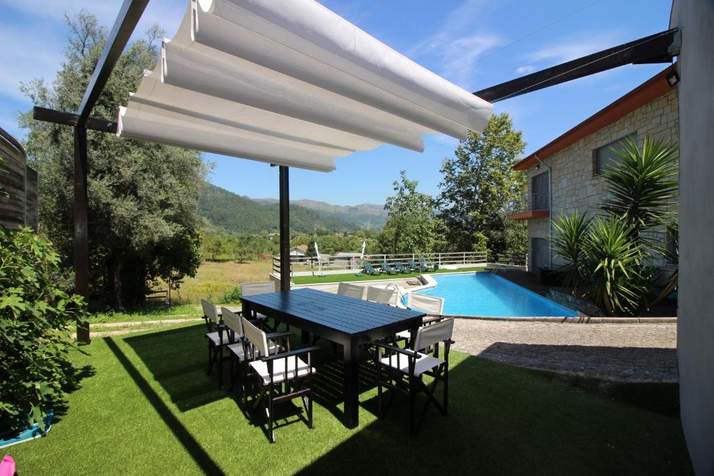 eine Terrasse mit einem Tisch, Stühlen und einem Pool in der Unterkunft Casa de Paredes Secas in Amares