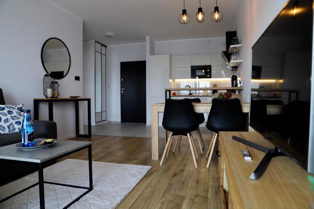 a living room with black chairs and a kitchen at Apartament Gdańsk Baltica Towers 7floor in Gdańsk