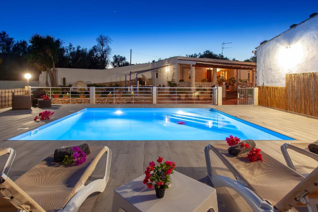 a swimming pool with chairs and a table and a house at VillaBlanca in Sant Rafael