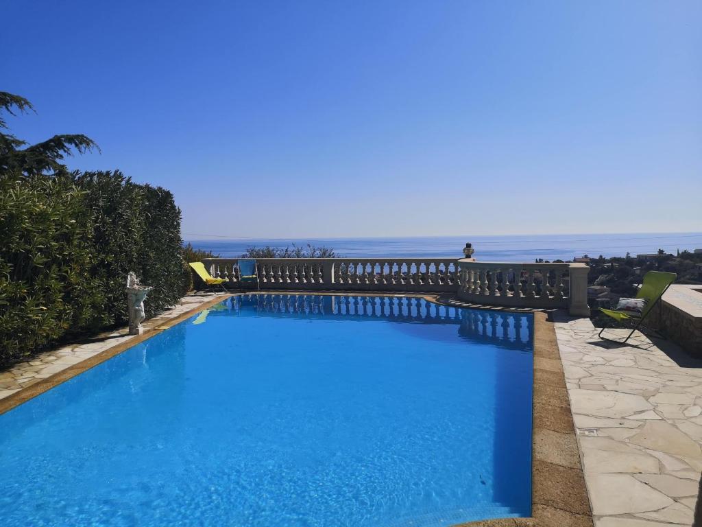 une grande piscine bleue avec l'océan en arrière-plan dans l'établissement Villa ANTINEA, A SAINT AYGULF, PISCINE PRIVEE, VUE MER PANORAMIQUE, à Fréjus