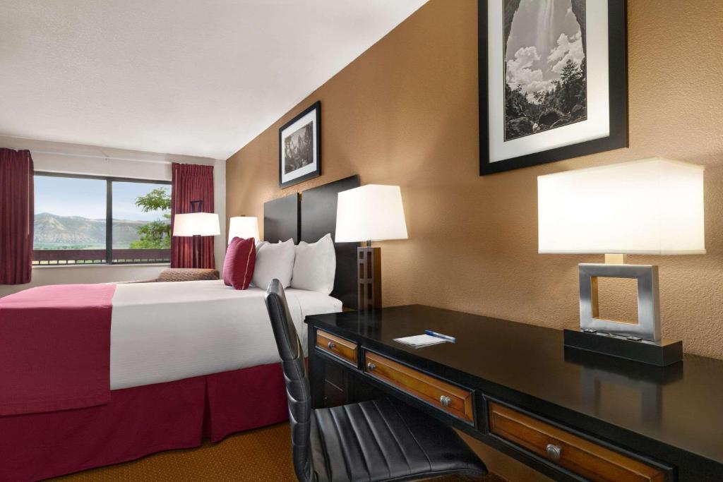 a hotel room with a bed and a desk at Baymont by Wyndham Cortez in Cortez