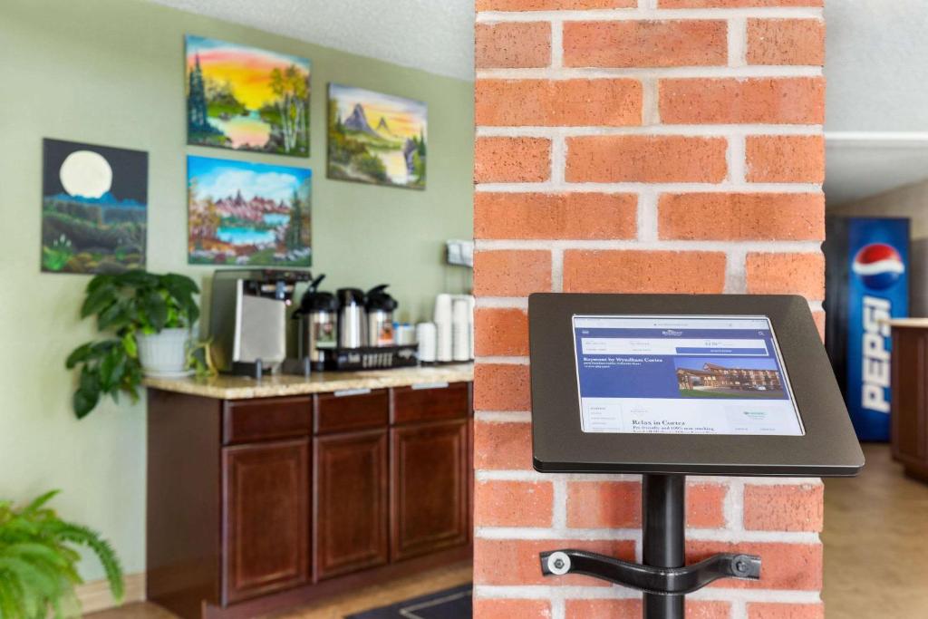 a laptop computer on a stand next to a brick wall at Baymont by Wyndham Cortez in Cortez