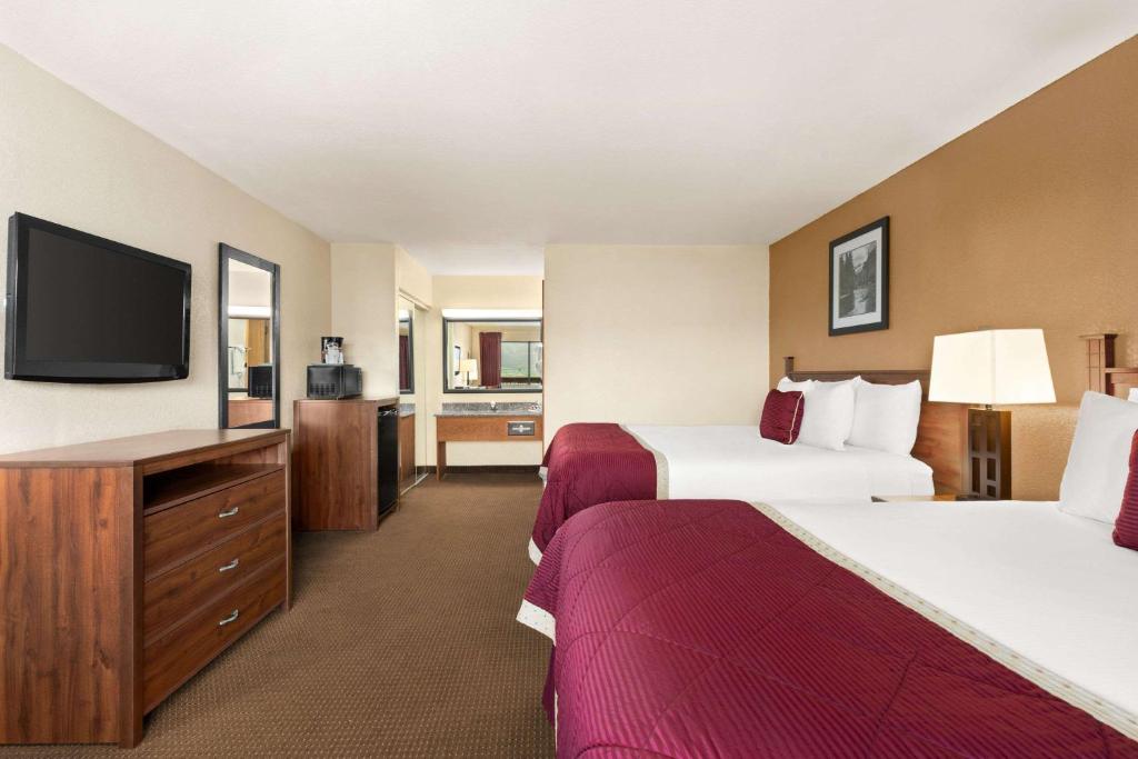 a hotel room with two beds and a flat screen tv at Baymont by Wyndham Cortez in Cortez