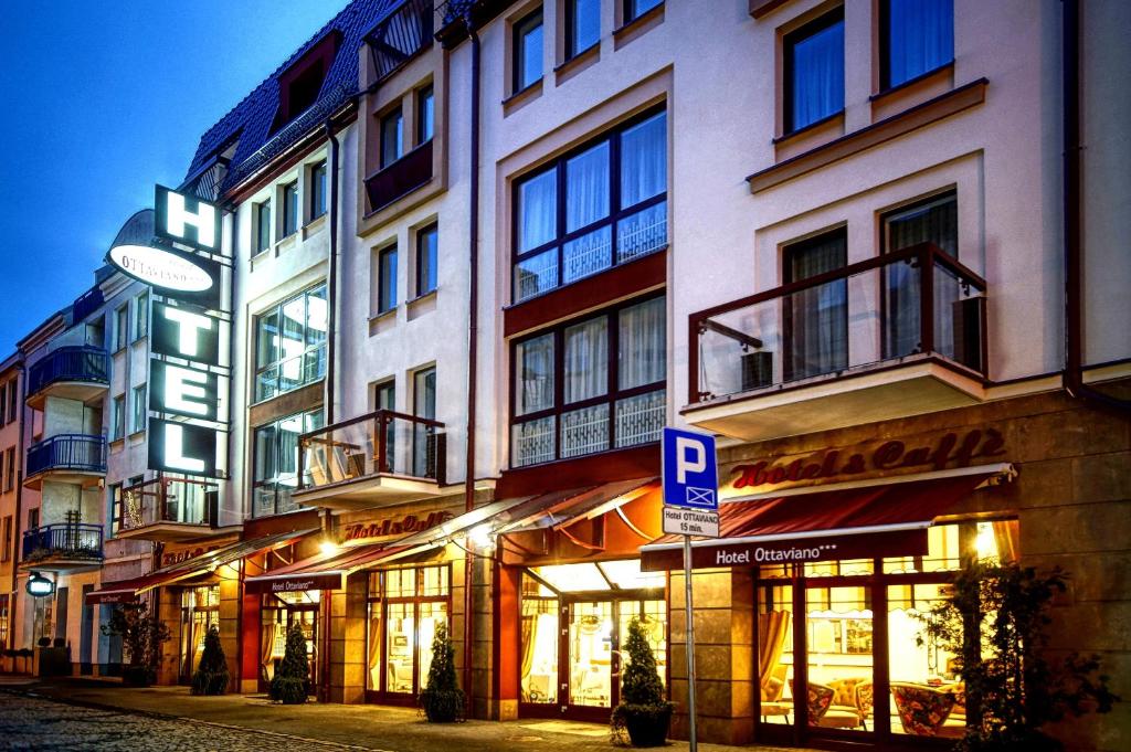 Evening facade of Hotel Ottaviano, illuminated vertical sign and warmly lit ground-floor windows.
