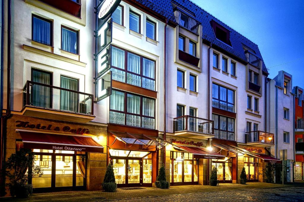 Multi-story hotel façade at dusk with illuminated ground-floor cafes and warm street lighting