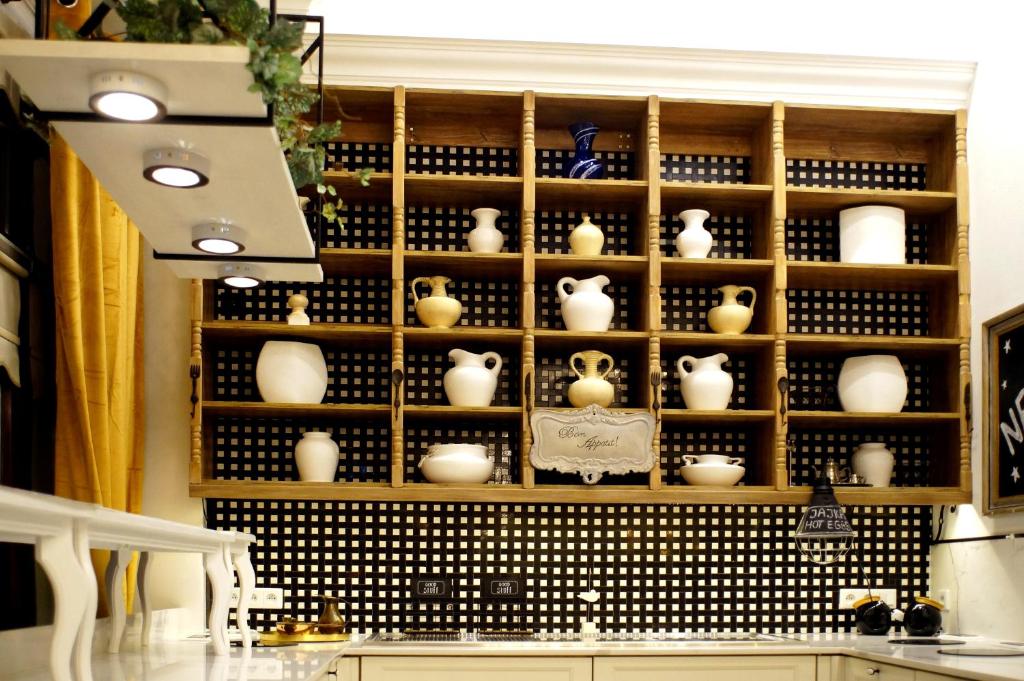Wooden cubby shelves displaying white ceramic vases above a tiled backsplash and countertop.