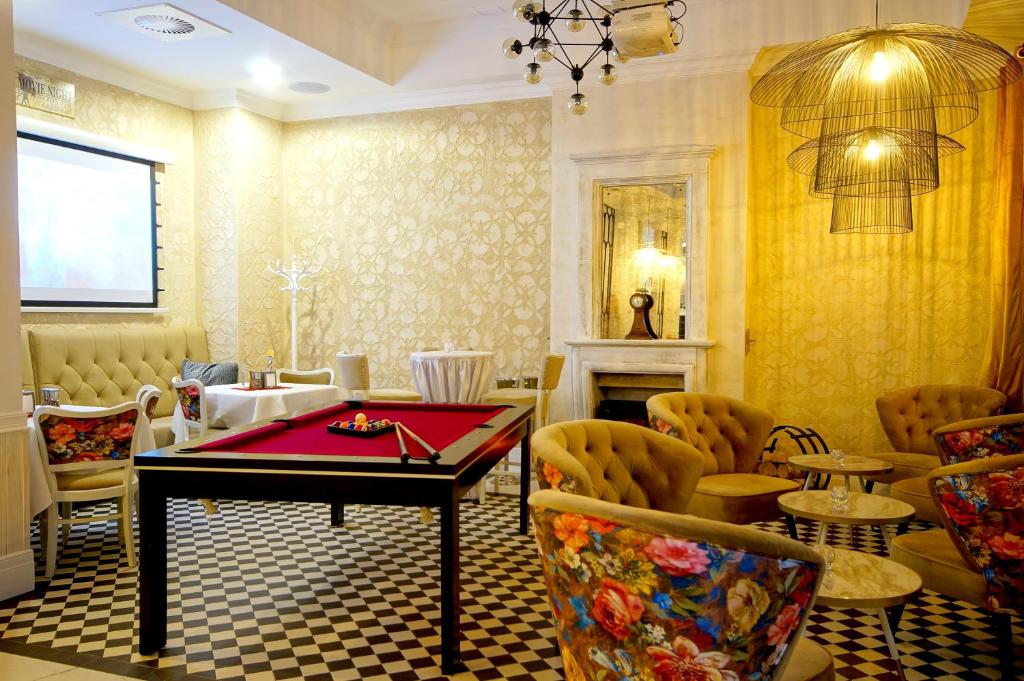 Red pool table centered on black-and-white checkered floor, surrounded by floral-patterned chairs and tufted seating.