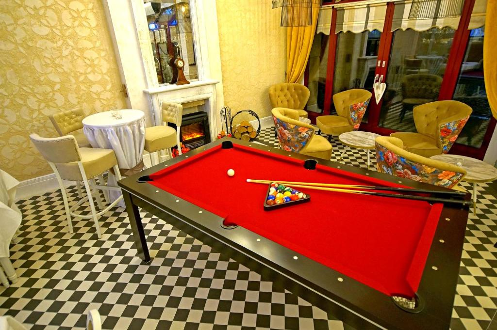 Wide lounge view featuring pool table, round tables, floral armchairs and rows of dining tables.