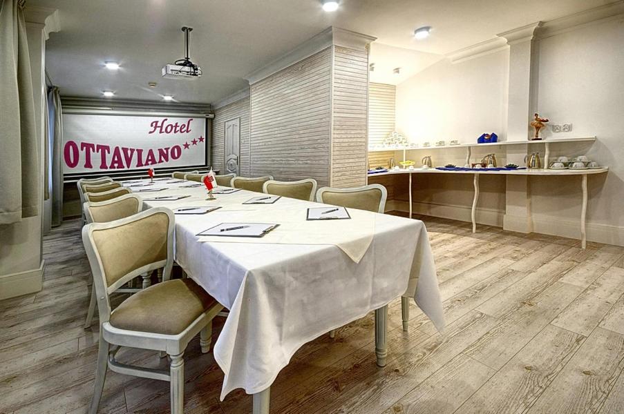 Meeting table with notepads, cushioned chairs and a refreshment counter stocked with cups and kettles.
