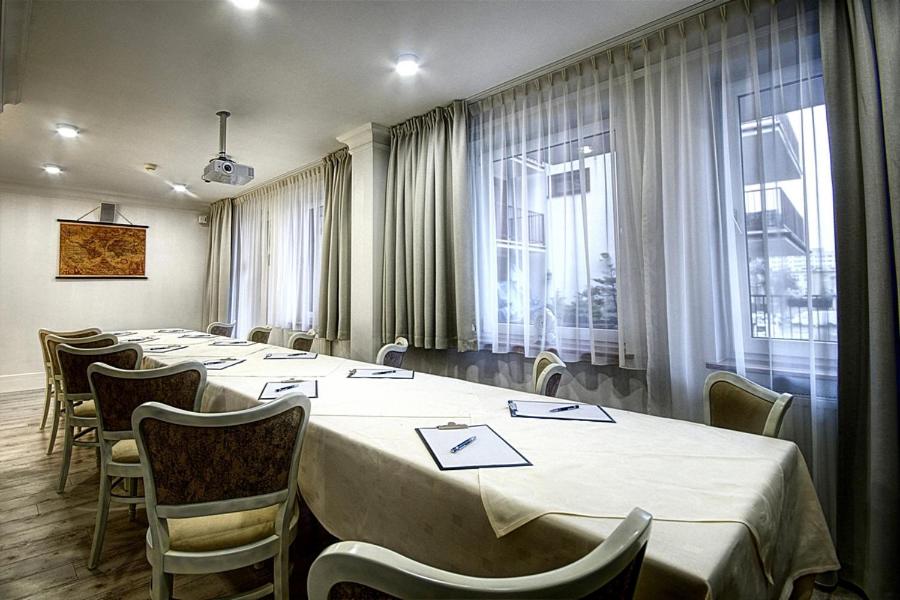 Long conference table with white cloth, notepads and chairs beneath a ceiling-mounted projector.