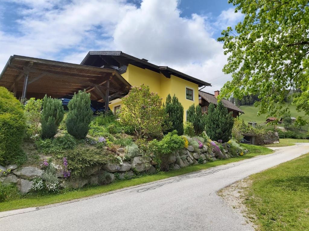 a yellow house with a stone wall next to a road at Haus Silvia Kraml in Schladming
