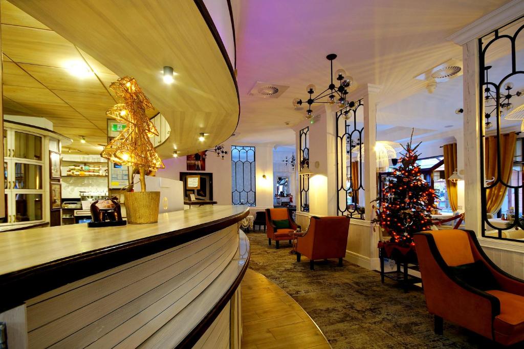 Warm lobby view with curved counter, armchairs and decorated Christmas tree near windows.