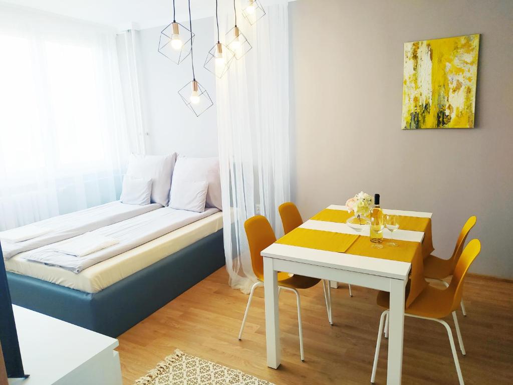 Habitación con cama, mesa y sillas. en Lora Apartman en Nyíregyháza