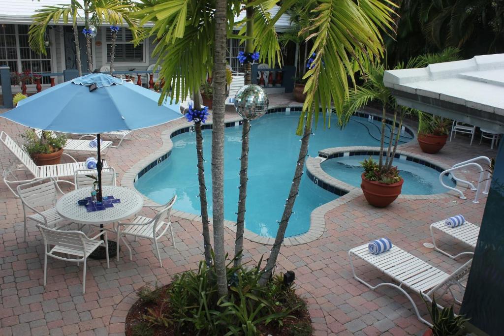 a pool with chairs and a table and an umbrella at Coral Reef Guesthouse in Fort Lauderdale