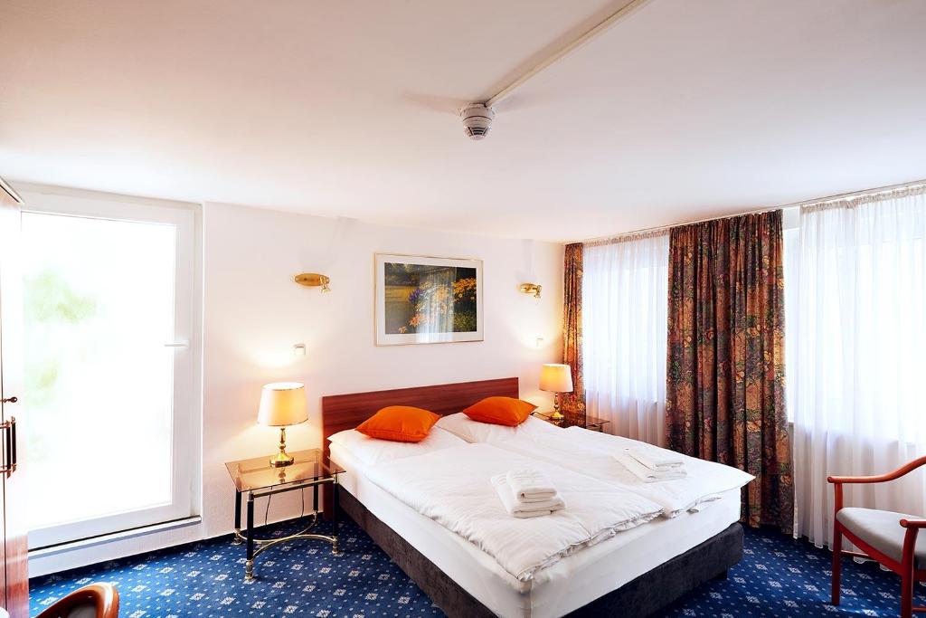 ヴィースバーデンにあるRing Hotelのベッドルーム1室(大型ベッド1台、オレンジ色の枕付)