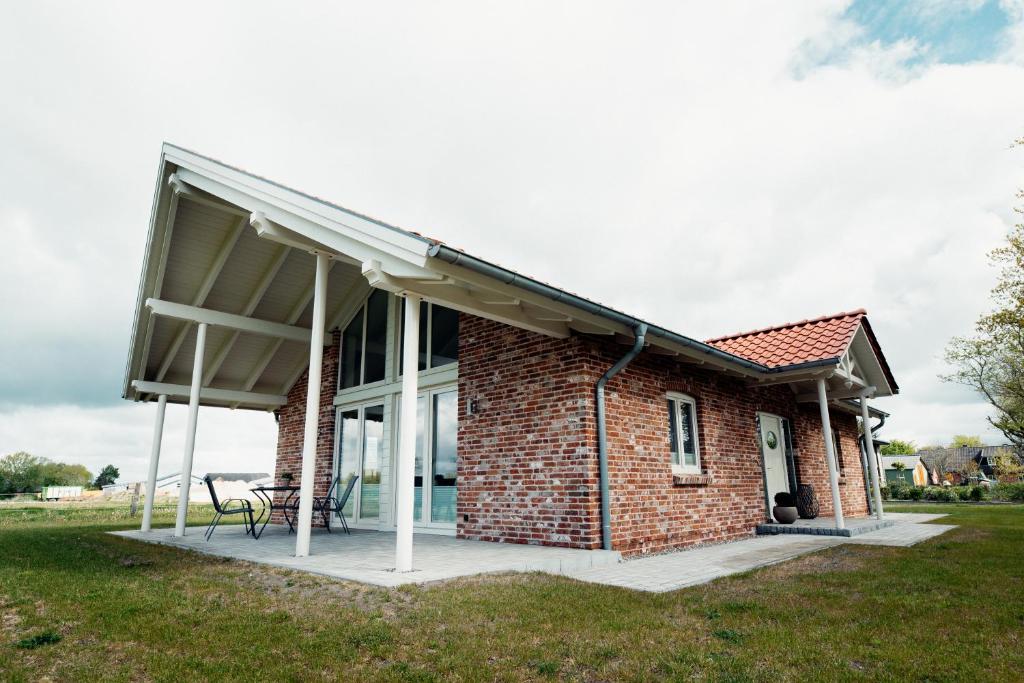 a brick house with a porch and a patio at Ferienhaus Loheide - mit Sauna in Langenhorn