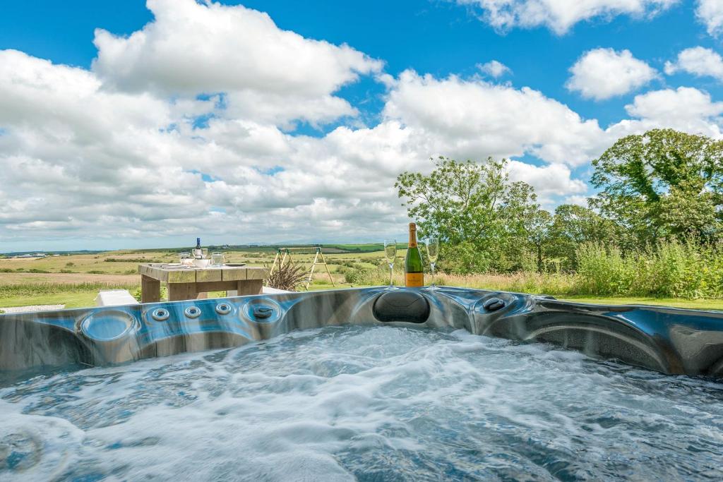 a hot tub with water in a field at Ty Carmel - Carmel House in Llanerchymedd