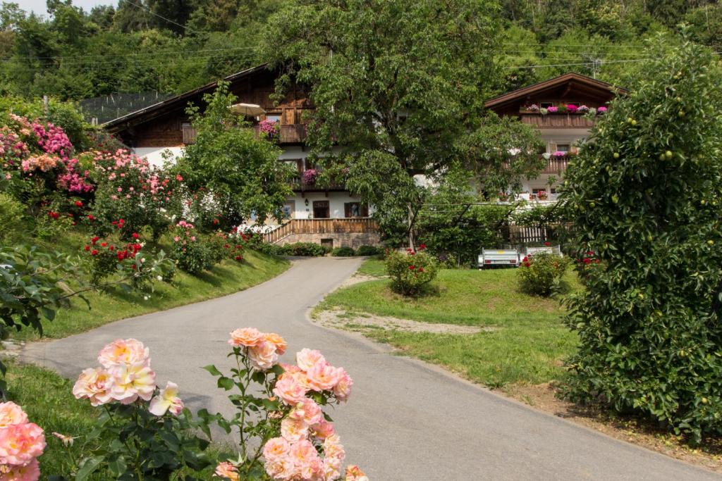 a road in front of a house with flowers at Appartements Kirchtalhof in Lana