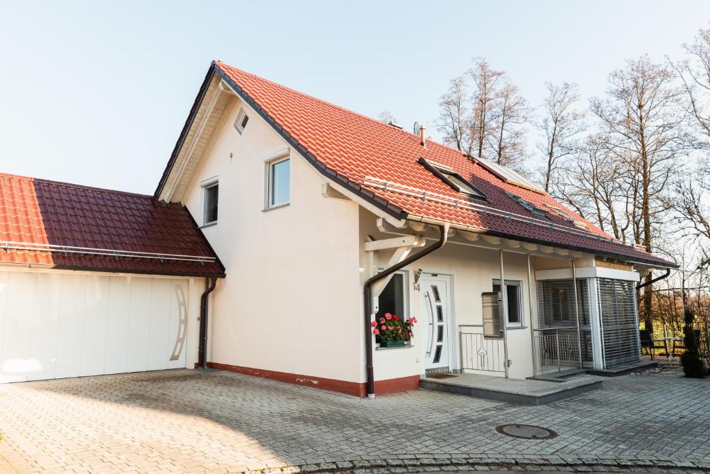 a white house with an orange roof and a driveway at Ferienwohnung "Johann" in Meckenbeuren