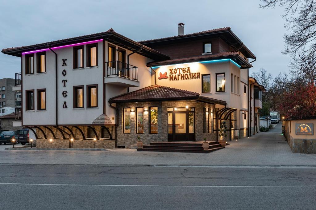 a building with a sign for a restaurant at Семеен хотел Магнолия in Kazanlŭk