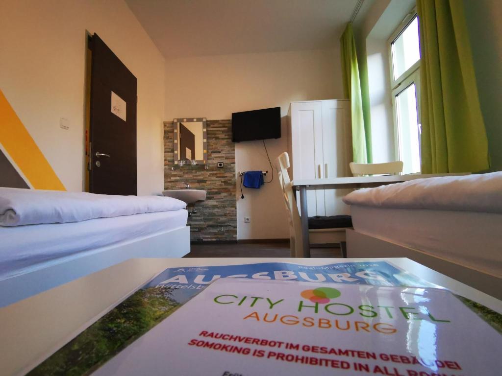 um quarto com duas camas e uma mesa com um livro em City Hostel em Augsburg
