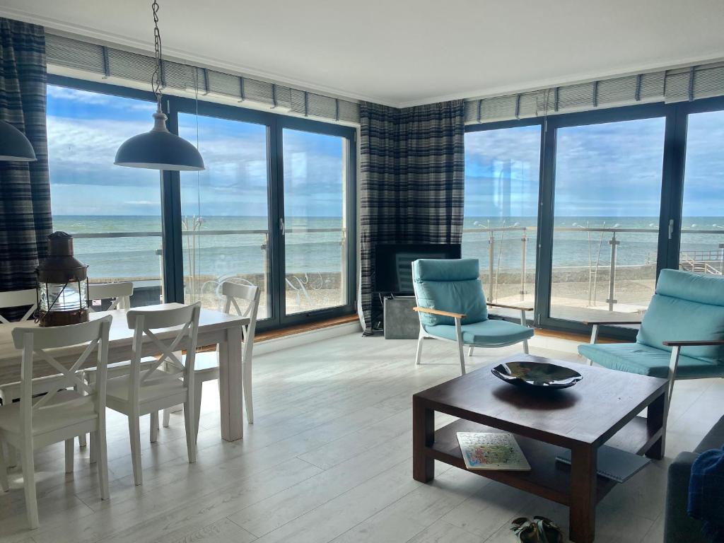 a living room with a table and chairs and the ocean at Apartament Błękitny przy Latarni in Darłowo