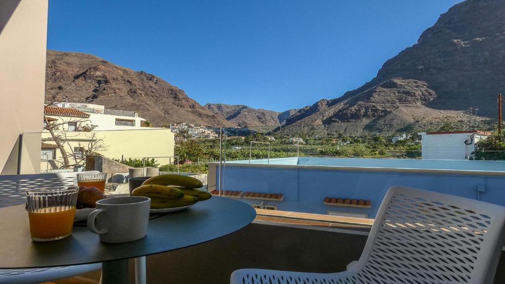 a table with a bowl of fruit on a balcony with mountains at El Guanche B in Valle Gran Rey