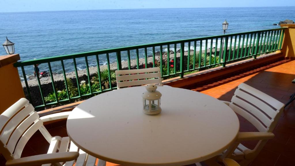 a white table and chairs on a balcony with the ocean at La Casa Grande in Valle Gran Rey