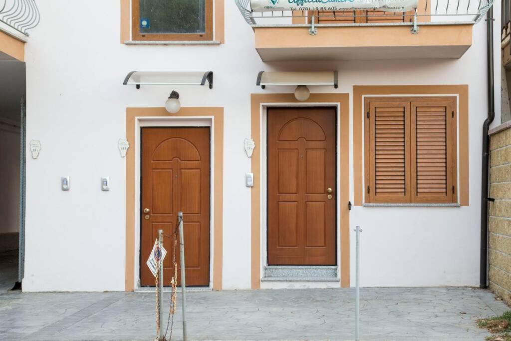 duas portas castanhas num edifício branco em Appartamento Lungomare em SantʼAntioco Ponti