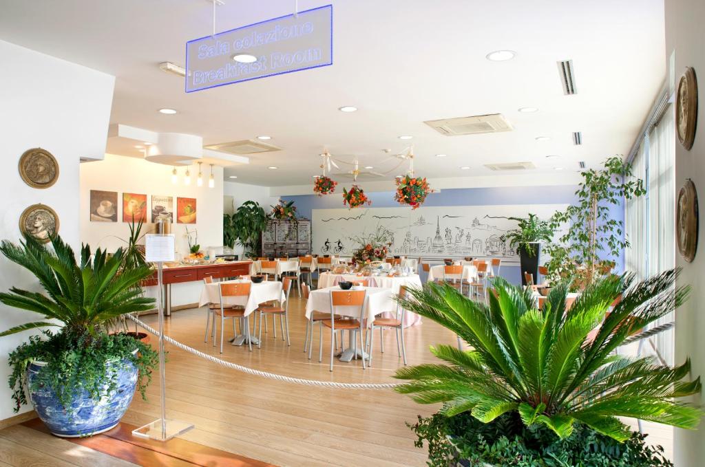 um restaurante com mesas, cadeiras e plantas em Hotel Master em Turim